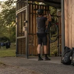 Camping velo : cyclotouriste gare un vélo sécurisé dans un abri couvert, accueil velo
